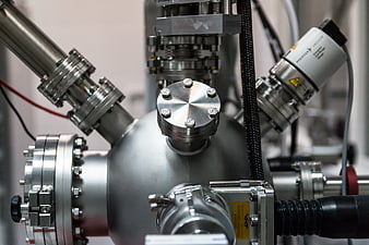 Close-up of industrial metal vacuum chamber with pipes and sensors