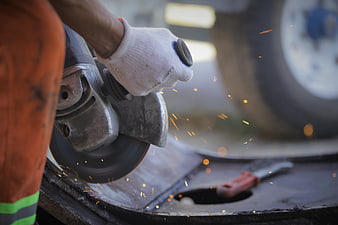 Close-up of worker using angle grinder with flying sparks