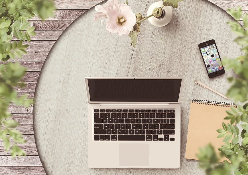 Flat lay workspace with laptop, smartphone, and notebook on wooden table