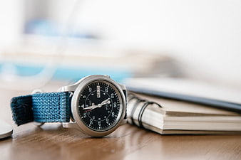 Analog Watch with Blue Strap on Wooden Desk