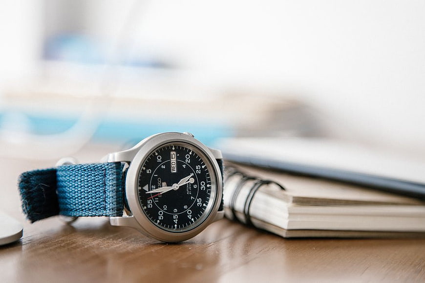 Analog Watch with Blue Strap on Wooden Desk