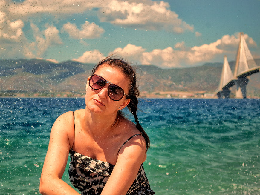 Woman on Boat Splashed by Sea with Bridge Background