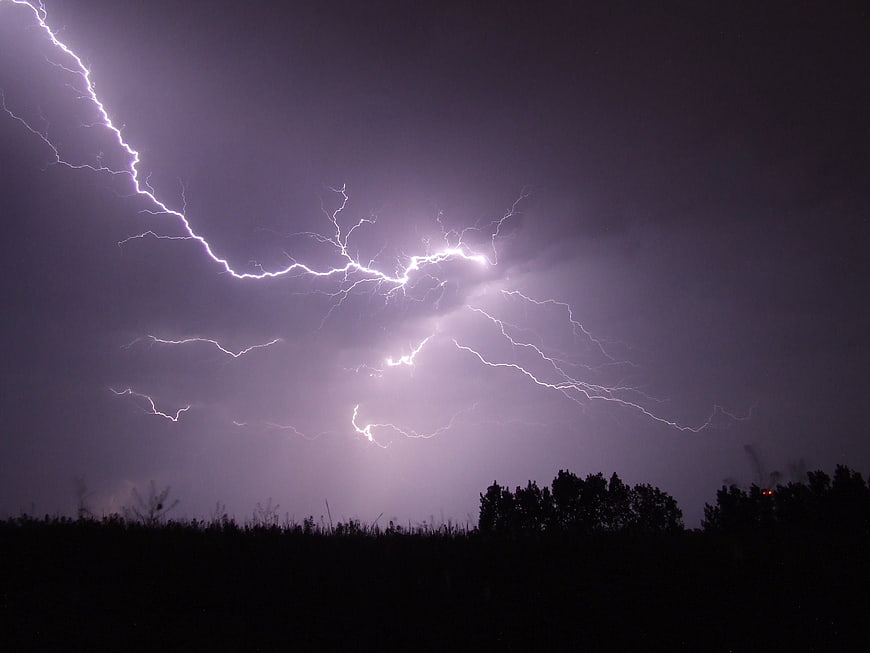 Dramatic lightning bolt striking across dark stormy night sky
