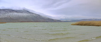 Panoramic view of a lake with snowy mountains and reeds