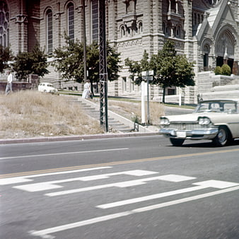Vintage white classic car driving past historic stone church