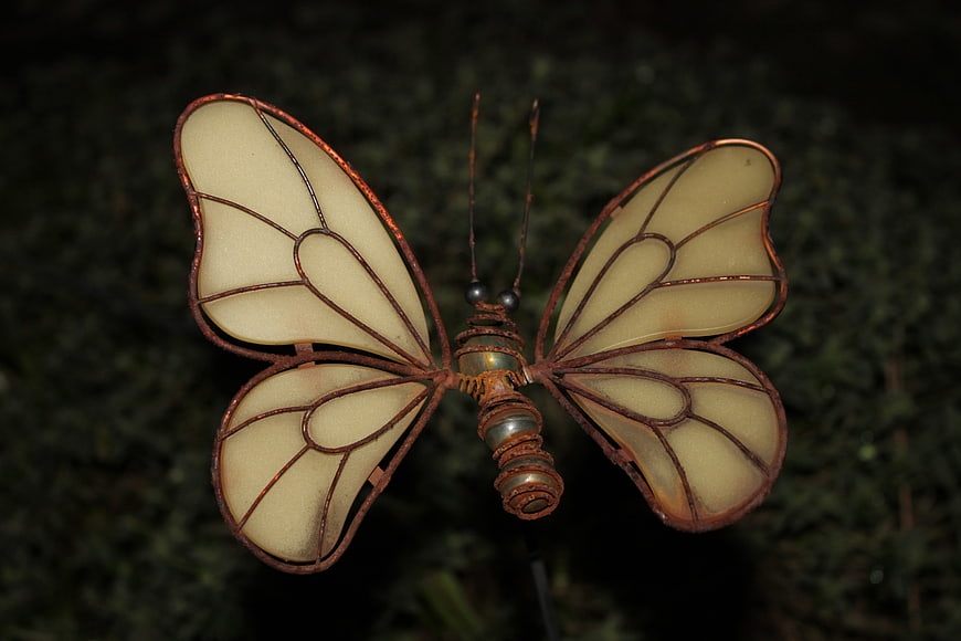 Rusty metal butterfly garden ornament at night