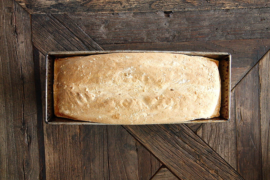 Freshly Baked Loaf of Bread in Pan on Rustic Wood