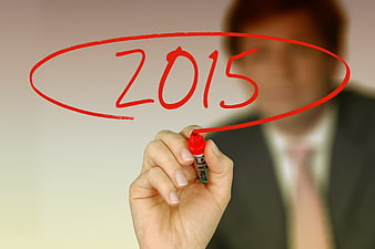 Businessman writing 2015 on transparent screen with red marker