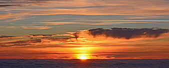 Panoramic sunset over ocean with dramatic clouds and golden light