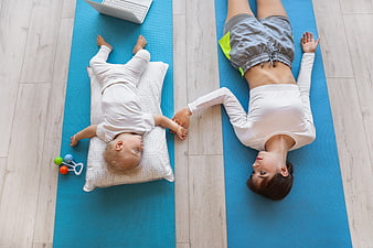Top view of mother and baby resting on yoga mats