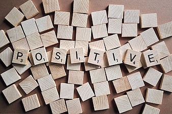 Positive spelled with wooden letter tiles on brown background