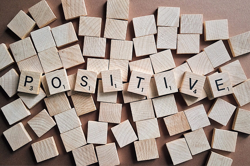 Positive spelled with wooden letter tiles on brown background