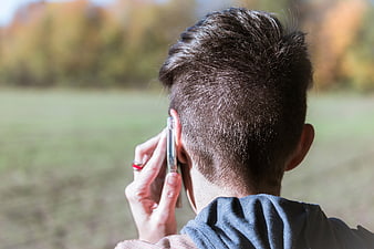 Back view of person talking on smartphone in autumn park