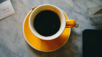 Top View of Black Coffee in Yellow Mug on Marble Table