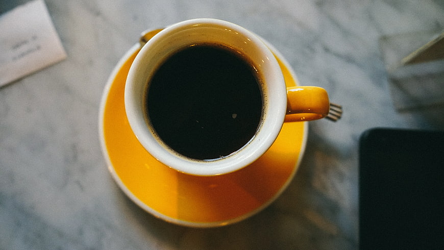 Top View of Black Coffee in Yellow Mug on Marble Table