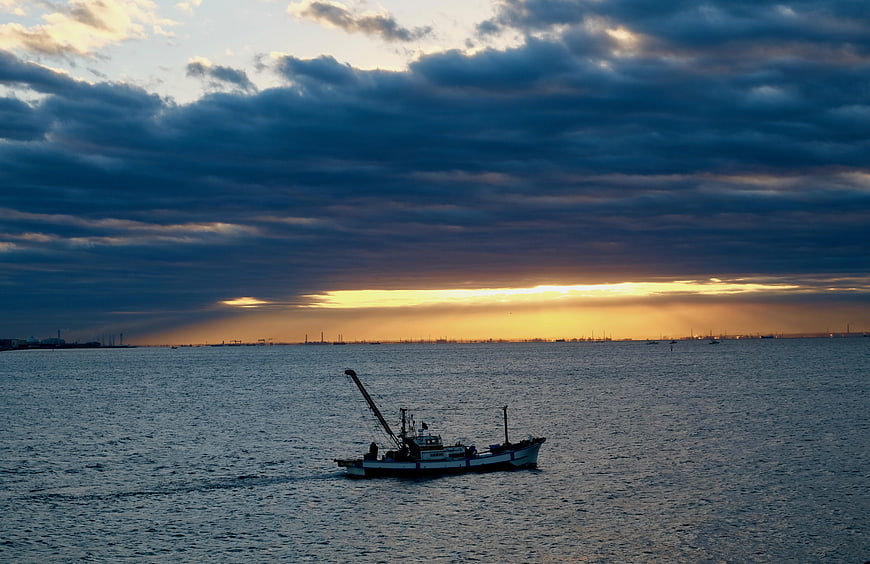 Fishing boat on Tokyo Bay at sunrise with dramatic clouds