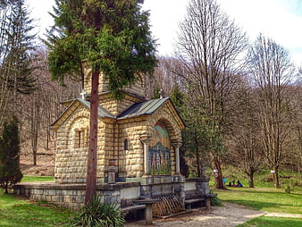 Small Orthodox stone chapel in a forest park with mosaic