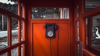 Vintage black rotary telephone in red wooden phone booth