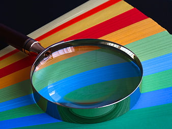 Magnifying glass on colorful rainbow paper stack