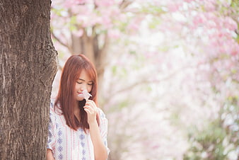 Young Woman Smelling Cherry Blossom in Spring Park