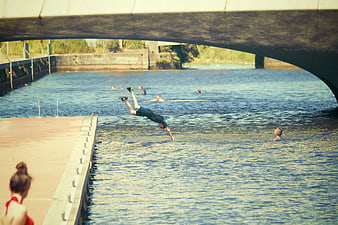 Man Diving into River Under Concrete Bridge