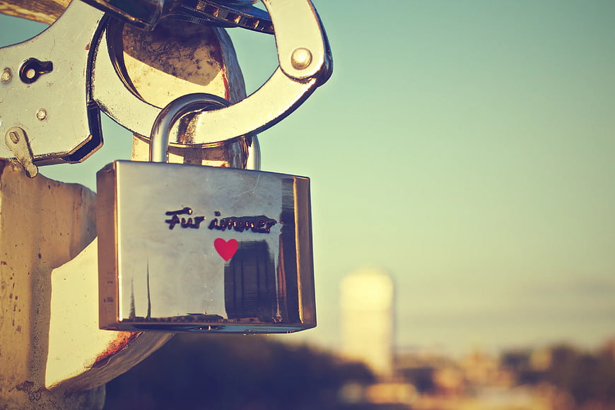 Silver padlock with engraved heart on bridge railing