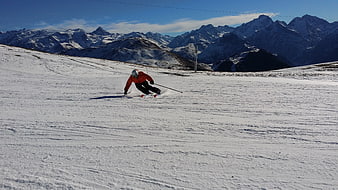 Skier in red jacket carving turn on snowy mountain slope