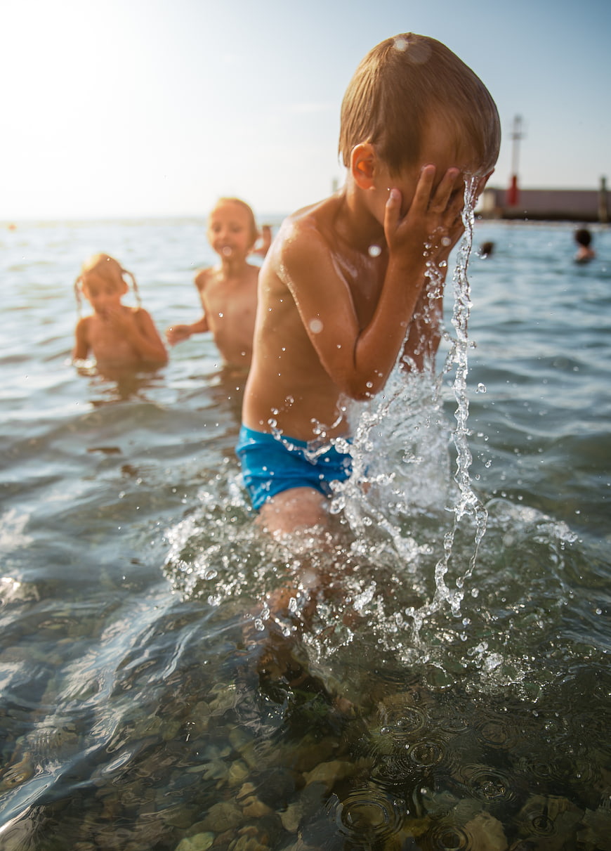 Young boy splashing water in the sea with friends
