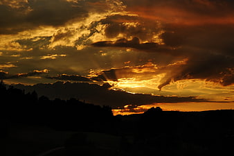 Dramatic sunset with golden sun rays breaking through clouds