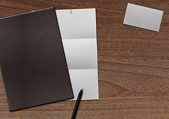 Brown leather notebook and blank paper on wooden desk