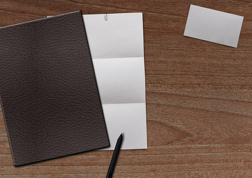 Brown leather notebook and blank paper on wooden desk