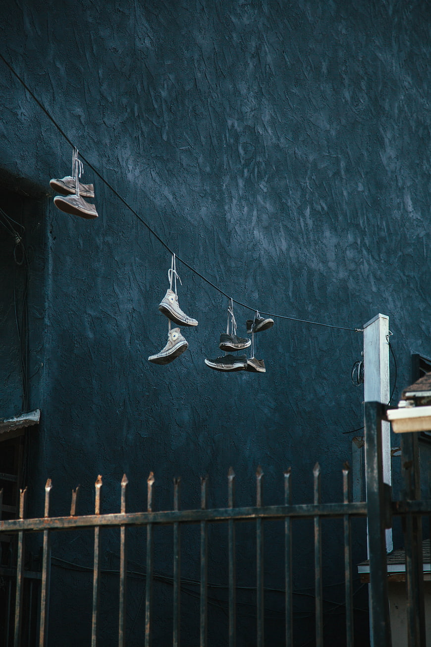 Sneakers hanging on wire against blue wall