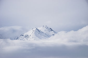 Snowy mountain peak emerging from thick clouds