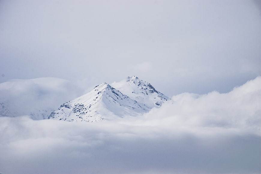 Snowy mountain peak emerging from thick clouds