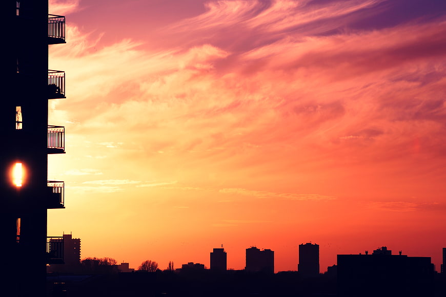 Vibrant Sunset Skyline with Silhouetted City Buildings