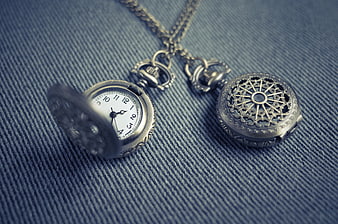 Vintage silver pocket watch and locket on blue denim