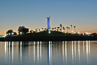 Lighthouse with blue light reflecting in water at dusk