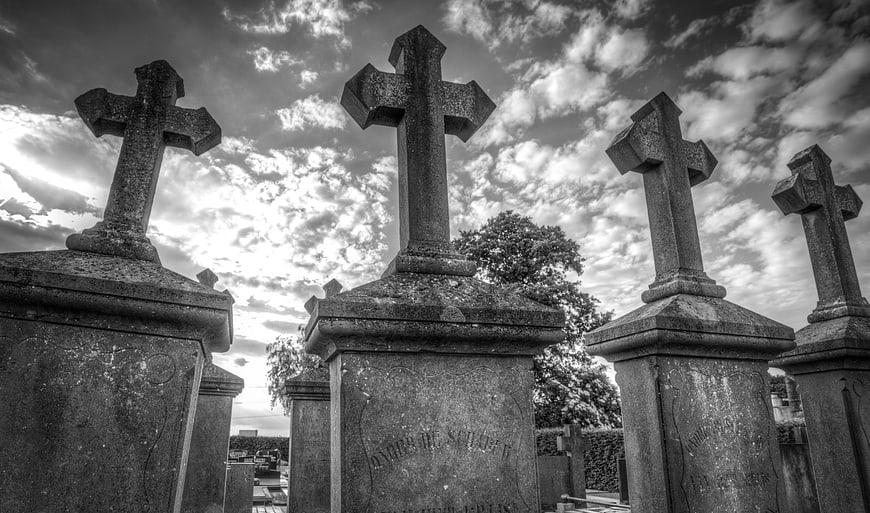 Black and white old cemetery crosses against dramatic sky