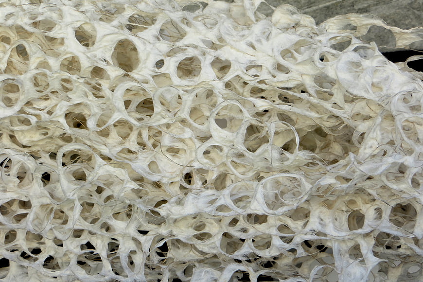 Close-up of white fibrous paper pulp texture with holes