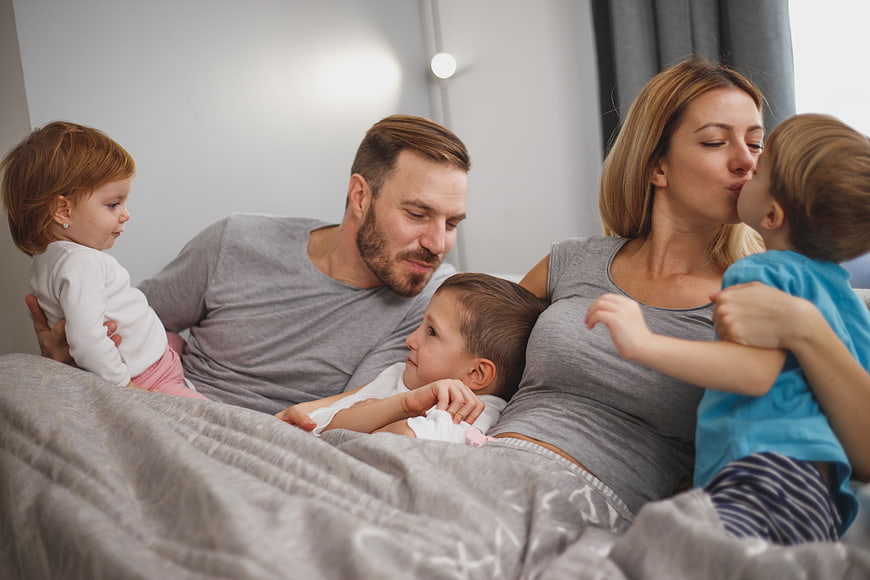 Happy family cuddling together in bed with children
