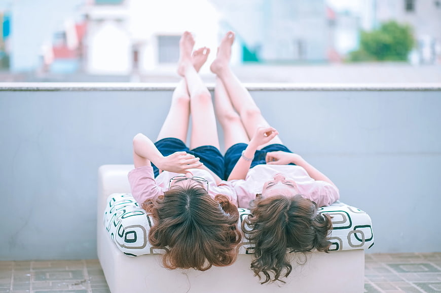 Two women relaxing on a rooftop sofa looking up