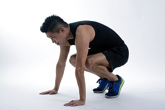 Athletic man in sprinter starting position on white background
