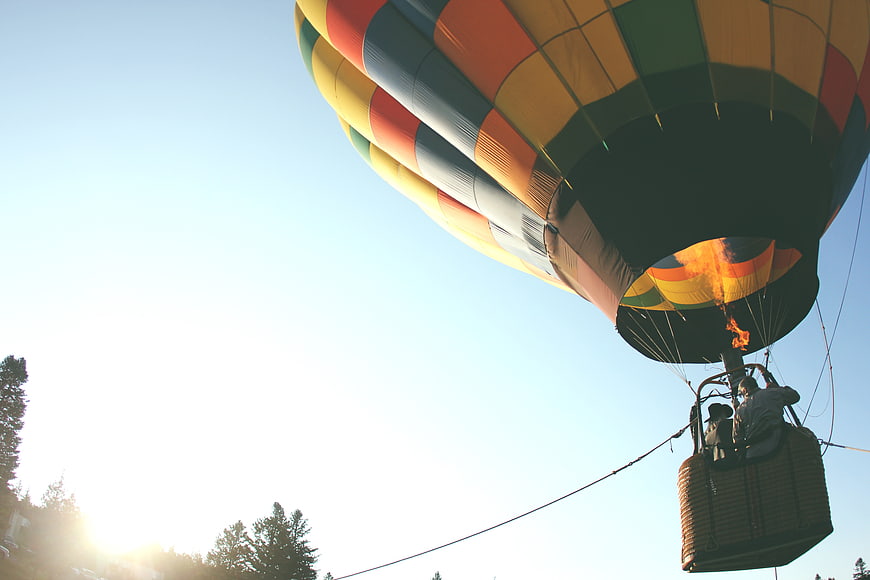 Colorful Hot Air Balloon Launching with Flame Against Blue Sky