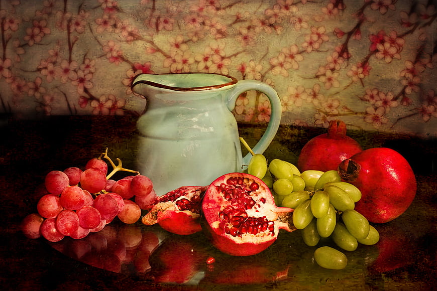 Vintage still life with pomegranates, grapes, and ceramic pitcher