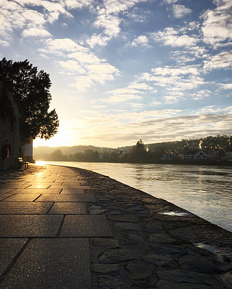 Sunset River Promenade with Stone Path and Cloudy Sky