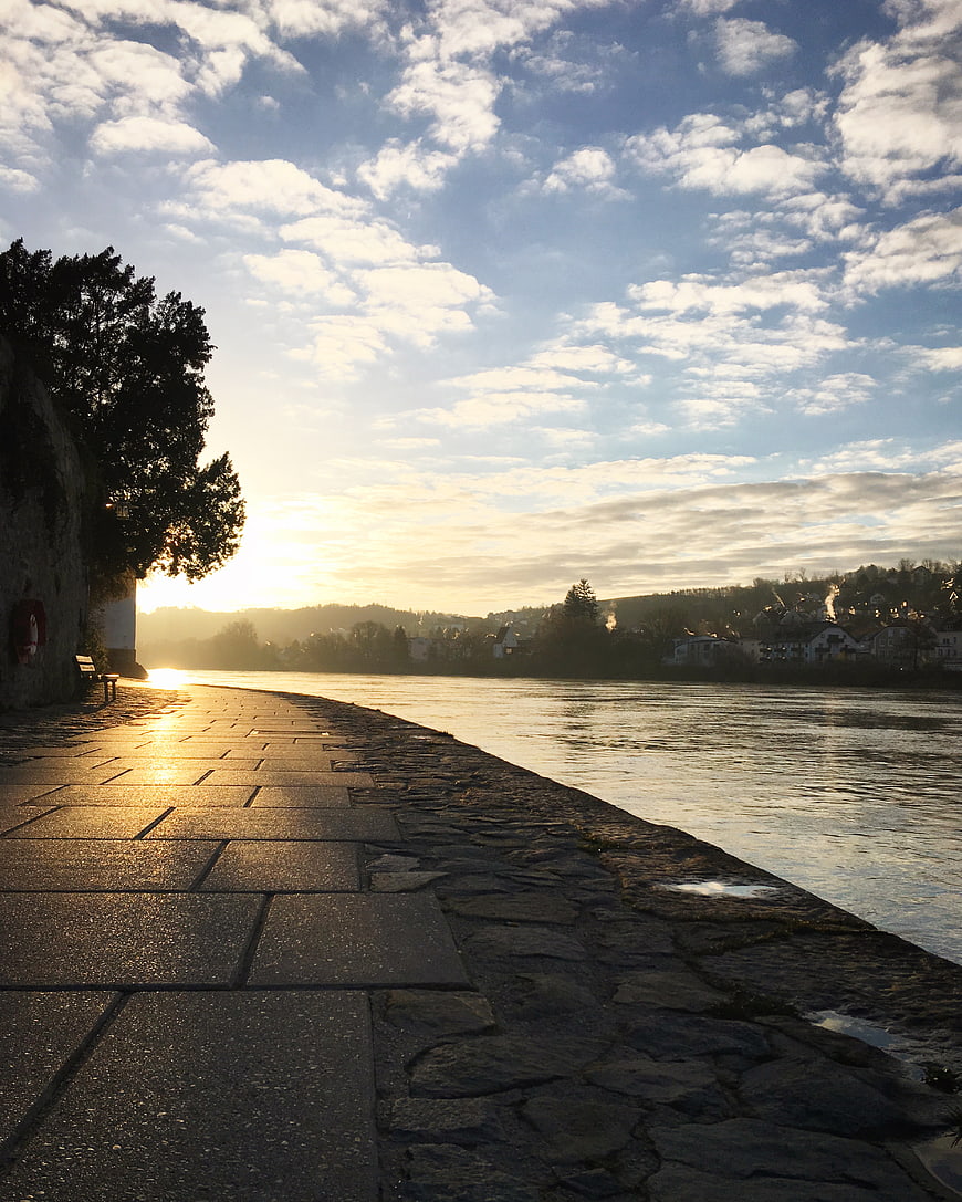 Sunset River Promenade with Stone Path and Cloudy Sky