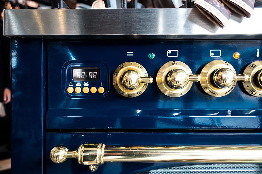 Close-up of vintage blue oven with brass knobs and handle