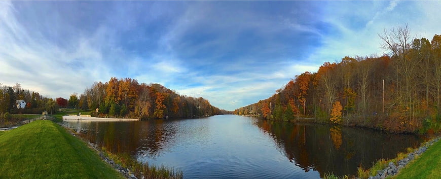 Panoramic autumn river landscape with colorful foliage and blue sky