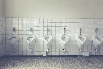 Row of white urinals in tiled public restroom