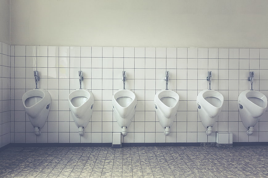 Row of white urinals in tiled public restroom